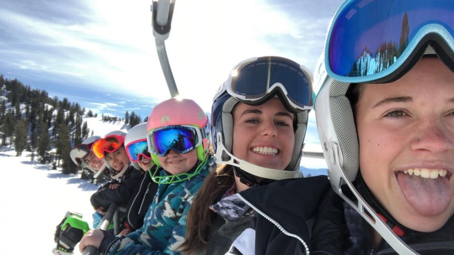 Soph Maclean, Gigi Taylor, and more of the ski team smile big on the chair lift.